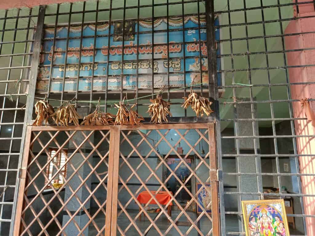 A view of Hanuman temple in Bangalore with prayer offerings and a vibrant deity painting inside.